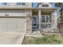 The front of the house boasts brick accents around the garage door and front porch, and white porch rails at 10065 Cairns Ct, Highlands Ranch, CO 80130