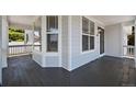 Inviting covered porch with neutral tone wood floor, bright white columns and light blue house siding at 5009 Mt Osage St, Frederick, CO 80504