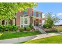 Lovely home showcasing a manicured lawn, mature trees, and a cozy front porch at 8318 Devinney Ct, Arvada, CO 80005