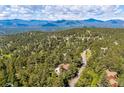 Scenic aerial view of a home nestled within a lush, green forest with mountains in the distance at 24999 Grandview Ave, Golden, CO 80401