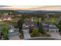 Expansive aerial view of a home nestled amongst lush greenery and rolling hills, with mountain views at 7071 Turweston Ln, Castle Pines, CO 80108
