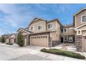Attractive townhouse with beige siding, stone accents, and attached two car garage at 14902 E Poundstone Dr, Aurora, CO 80015