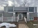 Charming two-story home featuring a cozy front porch, gray siding, and brick accents, creating a welcoming curb appeal at 15716 E Temple Pl, Aurora, CO 80015