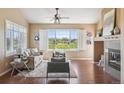 Cozy living room featuring hardwood floors, a fireplace, neutral paint, and a large window with shutters at 22455 E Plymouth Cir, Aurora, CO 80016