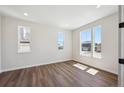 Bright bedroom with sleek wood flooring, complemented by natural light streaming through several windows at 5583 Riverbend Ave, Firestone, CO 80504