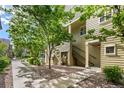 Charming exterior view showing the building facade and mature trees lining the sidewalk at 5444 Zephyr St # 203, Arvada, CO 80002