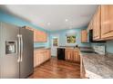 Well-lit kitchen features wood cabinets, stainless steel refrigerator, and updated appliances at 7834 S Windermere Cir, Littleton, CO 80120