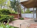 Backyard patio surrounded by lush greenery, a brick wall, garden area, and concrete tile at 2500 S York St # 116, Denver, CO 80210