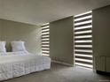 Bright bedroom with a white comforter, carpet, and window blinds for light and privacy at 2500 S York St # 116, Denver, CO 80210