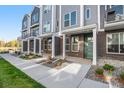 A modern townhome boasts brick accents, stylish gray siding, a welcoming covered porch, and lush landscaping at 888 S Valentia St # 101, Denver, CO 80247