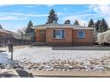 Brick ranch home with snowy lawn and carport at 4830 W Vassar Ave, Denver, CO 80219