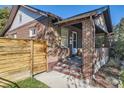 View of the brick home featuring an inviting front porch and fenced yard, providing privacy and charm at 1335 S Sherman St, Denver, CO 80210
