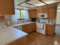Well-lit kitchen with wood cabinets, white appliances, and view from window above sink at 3262 S Salida Way, Aurora, CO 80013