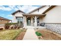 Inviting front porch with stone pillars, a seating area, and a beautifully landscaped walkway at 16500 Crosby Dr, Broomfield, CO 80023