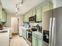 Well-lit kitchen with stainless steel appliances, charming sage-green cabinets, and a convenient laundry area at 6346 Fenton St, Arvada, CO 80003
