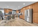 Modern kitchen with stainless steel appliances, wood cabinets, dining table, and sleek tile backsplash at 1922 Danube Way, Aurora, CO 80011