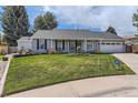 Well-maintained, single-story home with lush green lawn, stone accents, and mature trees, with ADT security sign at 7946 S Pennsylvania Ct, Littleton, CO 80122