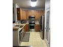 Updated kitchen featuring stainless steel appliances, wooden cabinets, and a convenient pantry door at 10457 W Hampden Ave # 104, Lakewood, CO 80227