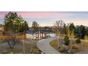 A well-maintained home with a circular driveway, mature trees, and a sunset backdrop at 9783 Zephyr Dr, Broomfield, CO 80021