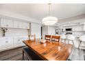 Open dining room with a large wooden table, stylish light fixture, and access to the kitchen at 3964 S Yosemite St, Denver, CO 80237