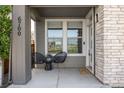 Charming front porch featuring a seating area with two chairs, brick accents, and a welcoming entrance at 6700 Clay St, Denver, CO 80221