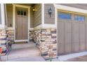 Inviting entryway with a solid front door, stone accents, and coach lights illuminating the facade at 12631 Glencoe St, Thornton, CO 80241