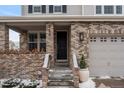 Close-up highlighting the front door, brickwork, and a two-car garage providing curb appeal at 4545 S Monaco St # 328, Denver, CO 80237