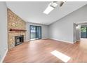 Spacious living room with wood floors, a stone fireplace, vaulted ceilings, skylight, and sliding door to the outside at 12023 E Harvard Ave # 203, Aurora, CO 80014