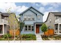 Inviting blue two-story home featuring a welcoming orange front door, manicured landscaping, and natural light at 10025 E 63Rd Ave, Denver, CO 80238