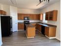 Spacious kitchen with wooden cabinets, an island, black appliances, and modern flooring at 20861 E 40Th Ave, Denver, CO 80249