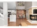 An open living space featuring a stone fireplace, hardwood floors and a modern kitchen at 6858 Zenobia St # 9, Westminster, CO 80030