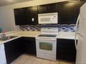 Kitchen featuring black cabinets, white appliances, patterned backsplash, light countertops, and tile floors at 7474 E Arkansas Ave # 18-12, Denver, CO 80231