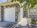 Close up exterior featuring a stone accent wall, three-car garage, and covered entry way at 10904 Eagle Run Dr, Parker, CO 80138