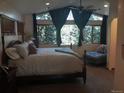 Sunlit main bedroom featuring large windows with wooded views and a cozy seating area at 21221 Colorado 103, Idaho Springs, CO 80452