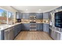 Updated kitchen featuring stainless steel appliances, granite counters, and hardwood flooring at 1232 Berganot Trl, Castle Pines, CO 80108