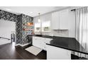 Stylish kitchen with floral wallpaper, white cabinets, black countertops, and open shelving at 1402 Meade St, Denver, CO 80204