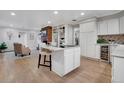 Open kitchen with an island, white cabinets, modern appliances, and hardwood flooring, flowing into the living room at 2290 E Columbia Pl, Denver, CO 80210