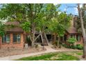 Brick apartment building with mature trees, manicured landscaping, and community outdoor access via stairs at 832 S Vance St # F, Lakewood, CO 80226
