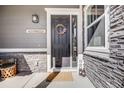 A classic black front door with wreath, welcome sign, and stone accents at 671 Green Mountain Dr, Erie, CO 80516