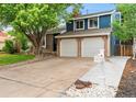 Two-story home featuring blue siding, brick accents, a two-car garage, and a well-maintained front yard at 7035 S Flower Ct, Littleton, CO 80128