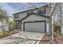 Two-story gray home featuring an attached two-car garage, lush lawn, and mature landscaping at 5316 S Rome St, Aurora, CO 80015