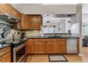 Modern kitchen with wood cabinets, black countertops, stainless steel appliances, and decorative backsplash at 2135 S Troy Way, Aurora, CO 80014