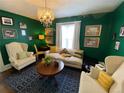 Cozy living room with vibrant green walls, an elegant chandelier, and comfortable seating arrangement at 421 E Alameda Ave, Denver, CO 80209