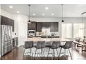 Contemporary kitchen featuring stainless steel appliances, a large island with bar seating, and dark wood cabinetry at 6723 Raritan Dr, Denver, CO 80221