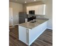 Bright kitchen features a granite countertop island, stainless steel refrigerator, and modern finishes at 7302 Arkansas Street, Frederick, CO 80530