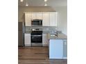 Modern kitchen featuring stainless steel appliances, granite countertops, and sleek white cabinetry at 7302 Arkansas Street, Frederick, CO 80530