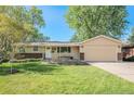 Inviting one-story home showcasing lush green grass, mature shade trees, and an attached garage at 8626 W Utah Ave, Lakewood, CO 80232