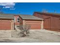 Home exterior with garages, set against a blue sky, featuring brick and siding accents at 2923 W Bryant Cir, Littleton, CO 80120