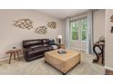 Cozy living room featuring a leather sofa, unique coffee table, and ample natural light at 24702 E Ontario Dr, Aurora, CO 80016