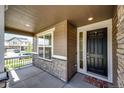 Inviting front porch with stone accents, a decorative front door, and ample space for relaxing outdoors at 960 S De Gaulle Ct, Aurora, CO 80018
